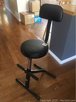 Front view of the black guitar chair showing padded round seat, backrest, and adjustable height mechanism.