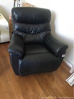 Front view of recliner in upright position on hardwood floor with other furniture in background
