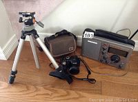 Grundig S350 radio, Fujifilm Finepix S camera with case, and Slik tripod displayed together on floor