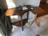 Photo of two wooden small tables side by side near a wall on tile floor with decorative knickknack items on the half moon table