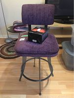 Full view of purple cushioned swivel chair with microphone box on seat.