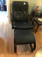 Black IKEA chair with padded seat and back, armrests, swivel base, showing wear and creasing.
