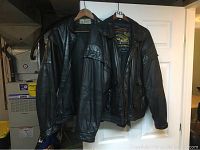 Two black leather jackets hanging on door, showing overall aged wear and condition