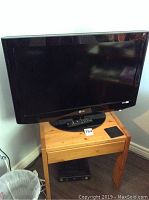 LG 32 inch TV on pine wood stand with remote on base of TV.