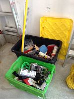 Photo showing black Rubbermaid bin with yellow lid and green Rubbermaid bin containing various items including gloves, cord and tools