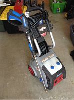 Full view of Briggs & Stratton pressure washer showing hose wrapped on trigger gun, water tanks, and wheels.