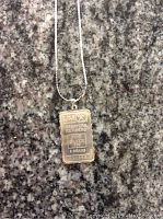 Photo of sterling silver pendant in detail showing inscriptions on the pendant.