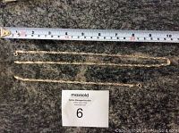 Photo showing two silver chain jewelry pieces laid flat next to a tape measure for size reference. Both have a detailed chain link design.