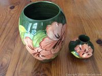 Two floral Moorcroft vases, one large one small, on wooden surface