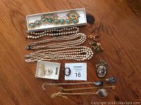 Full view of all vintage costume jewellery pieces including necklaces, brooches, and earrings laid out on wooden surface.
