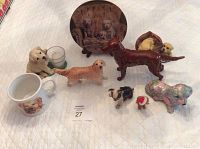 Overview of dog figurines, plate, mug, and candle holder showing all collectibles in the lot