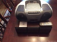 Panasonic boombox with speakers, top CD player, cassette deck, and remote control on wood table
