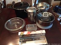 Full view of assorted kitchen pots, bowls, and canister arranged on a wooden table.