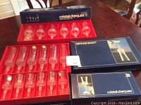 Displayed 24 Cristal d'Arques crystal glasses in original boxes, 12 each in two boxes. Glasses have diamond-cut pattern and thick stems.