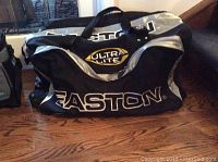 Large black and silver Easton Ultra Lite sports duffel bag on a wooden floor