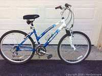 Side view of ladies mountain bike showing blue and white frame, front suspension, handlebar, seat, and wheels