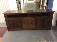 Front view of media unit showing overall design with open shelf, drawers, and cabinet doors