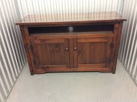Front view of a dark brown wooden media unit with a top shelf and two closed doors below.