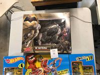 Photo showing new open box Air Hogs RC Batwing and Hot Wheels 18-piece car set with dinosaur figure