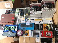 Overview of assorted electronics accessories including controllers, adapters, chargers, and paper.