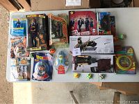 Full view of the lot on a table showing multiple collectible toys, action figures, and game items including boxed and loose pieces.