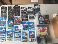 All items laid out on table including Hot Wheels cars, Wii Sing It, PS3 Dead Rising 2 and Star Wars Jedi Knight games