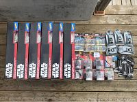 Photo showing six boxed Hot Wheels Star Wars Escape from Jakku playsets alongside other Star Wars collectibles including logo projectors, LCD watches, micro machines, and Infinity figures.