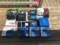 Photo showing multiple electronic items including PS4 headphones, tablets, various boxes of TV streaming devices, and accessories laid out on a wooden surface.