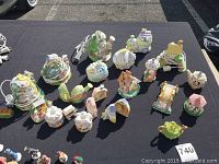 Overview of Easter-themed figurines including egg shaped houses, bunnies, small pastel spring homes and vehicles on a black tablecloth.