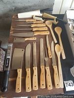 Full view of knife collection on a table showing knives with wooden handles, kitchen utensils, and sharpeners.