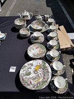 Full overview photo of the Myott China set laid out on a black cloth outdoors showing cups, plates, serving pieces.