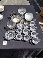 Clear glassware arranged on black cloth including mugs, bowls, cups, candy dish