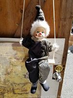 Full view of the clown doll hanging on wooden swing with detailed face and outfit visible