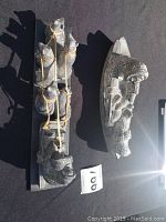 Photo of both soapstone carvings on black surface, one shaped like a boat with swan, the other a group of seals on wooden base
