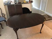 Oval table assembled, showing full top and carved legs.