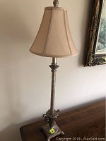 Side view of the full candlestick style lamp highlighting its height, fabric shade and base details.
