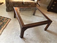 Full view of the coffee table in the room showing square shape and glass top