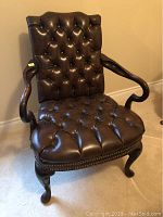 Front view of brown leather button tufted armchair