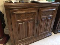 Full frontal view of the Ethan Allen solid wood cabinet showing two doors with carved pattern and metal ring handles.