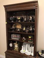 Full front view of the bookshelf showing four shelves with various decorative items placed on them to illustrate size and shelf spacing.