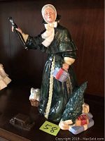 Front view of Royal Doulton Christmas Parcels figurine showing a woman holding parcels and a candle lighter.