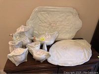 All nine wrapped pieces displayed on wooden sideboard: two trays at back, pots and bowls in front.