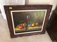 Full view of the signed still life painting on canvas within its ornate carved dark wood frame.