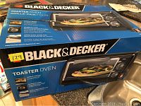 Box of Black & Decker toaster oven showing graphic of the oven with food inside, displaying brand name and product features.