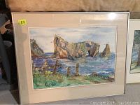 Framed watercolour painting depicting Percé Rock in a coastal setting with sea and sky. The painting is behind glass and mounted with a beige mat within a metallic frame.
