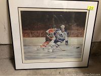 Full view of framed hockey print leaning against concrete wall