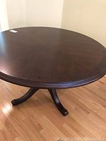 Photo showing the full round wooden dining table with pedestal base.
