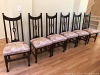 Six dark wood dining chairs in a row, showing full set and uniform style