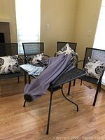 Full view of the patio set including table, four chairs with cushions, and umbrella folded on table.