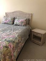 Wider view showing painted wicker headboard, matching nightstand, bedding and pillows